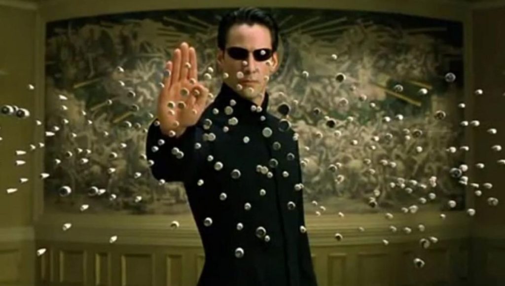 Keanu Reeves nei panni di Neo in Matrix, scena iconica con proiettili sospesi Scena di Matrix con Neo che ferma i proiettili in aria
