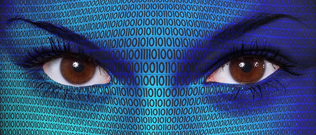 Occhi umani che emergono da uno sfondo digitale pieno di codice binario, simbolo dell’intelligenza artificiale che osserva, analizza e potenzialmente agisce in autonomia. Riferimento visivo alle backdoor AI e al controllo opaco dei modelli