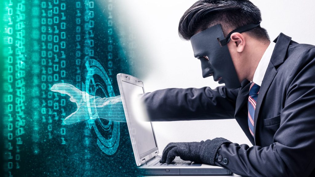 Hacker con maschera che ruba dati da un laptop: simbolo della gravità degli attacchi Policy Puppetry