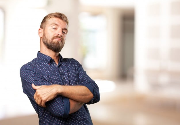 Uomo con barba a braccia incrociate, espressione sicura e sfidante
