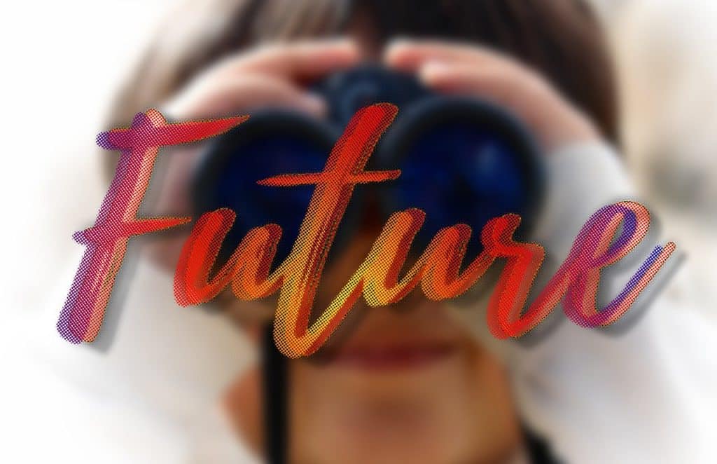 Scritta colorata “Future” in primo piano davanti a una persona sfocata che guarda dentro un binocolo, simbolo dello sguardo verso il futuro e l’innovazione