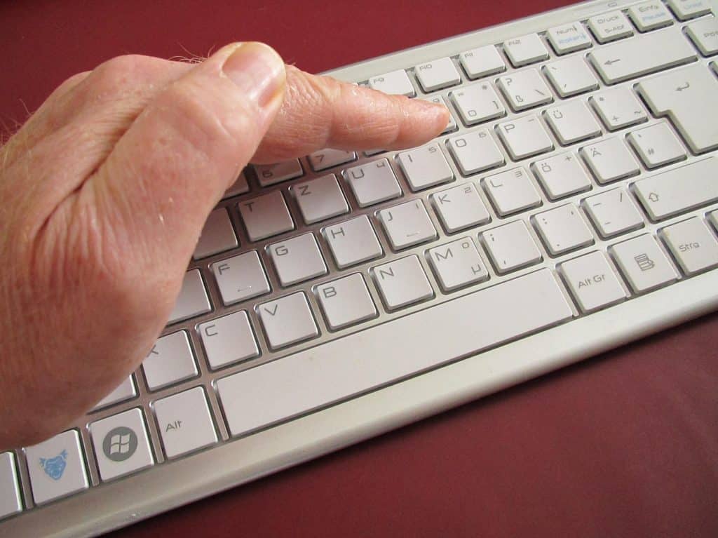 Mano pronta a premere un tasto sulla tastiera, simbolo delle decisioni che possono modificare la tutela della cifratura end-to-end
